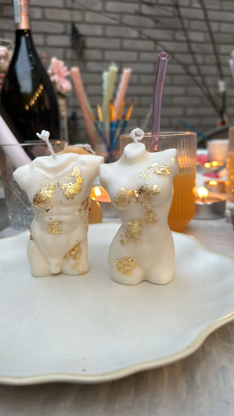 Twee beschilderde kaarsen in de vorm van een torso met bladgoud